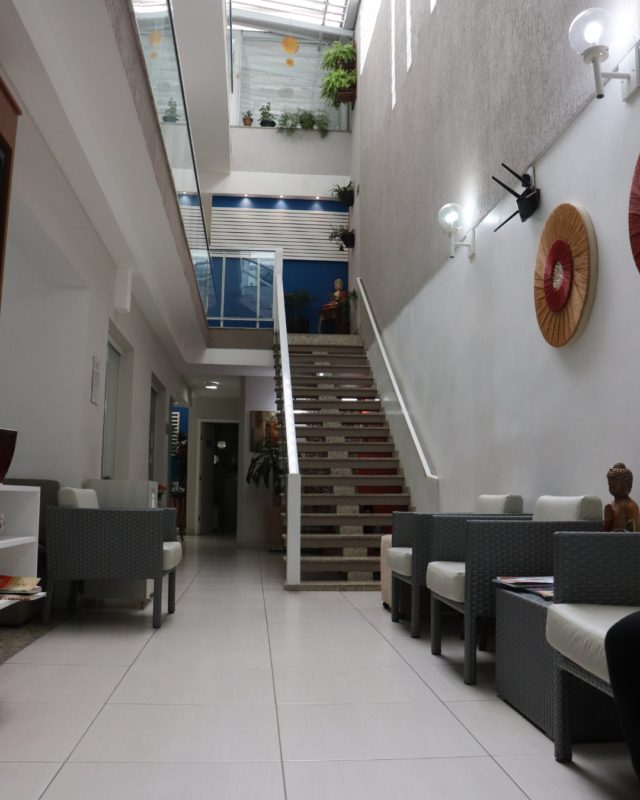 Área de espera da Saúde Integrada com poltronas acolhedoras e escada que dá acesso ao segundo pavimento, demonstrando a amplitude dos 600m² do espaço em São Bernardo do Campo.